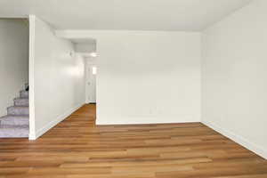 Unfurnished room featuring stairs and light wood-type flooring