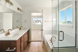 Bathroom featuring double vanity, wood finished floors, and a garden tub