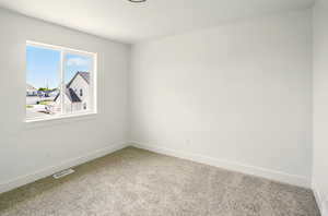 Spare room featuring carpet flooring and baseboards