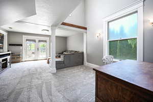 Living room with carpet floors, french doors, and a textured ceiling