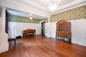 Sitting room with ornate columns, a decorative wall, wallpapered walls, wood-type flooring, and wainscoting