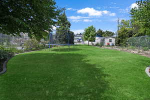 Fenced backyard with a trampoline and an outbuilding