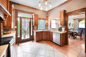 Kitchen featuring a chandelier, appliances with stainless steel finishes, light countertops, under cabinet range hood, and cabinetry
