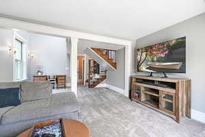 Living area with stairs, carpet flooring, and decorative columns