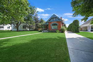 View of front of house with a chimney, a front yard, and brick siding