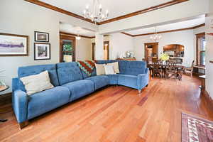 Living area with a chandelier, light wood finished floors, and ornamental molding