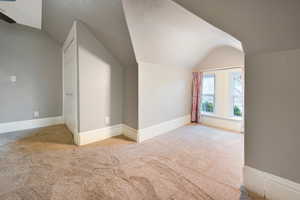 Additional living space featuring vaulted ceiling, carpet floors, and ceiling fan