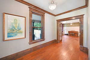 Corridor featuring a chandelier, wood-type flooring, ornamental molding, and french doors