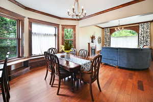 Dining room with a chandelier, healthy amount of natural light, crown molding, and hardwood / wood-style flooring