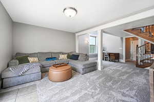 Carpeted living area with stairs and baseboards