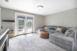 Living area featuring french doors, light tile patterned flooring, and light colored carpet