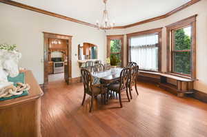 Dining space with a chandelier, arched walkways, crown molding, and hardwood flooring