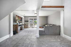 Living area featuring carpet, a textured ceiling, and french doors