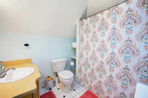 Bathroom with vanity, tile patterned floors, a shower with shower curtain, and vaulted ceiling