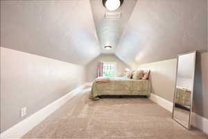 Bedroom featuring lofted ceiling, carpet floors, and a textured ceiling