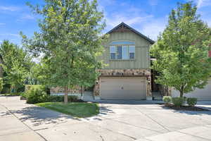 View of front of property featuring board and batten siding, concrete driveway, an attached garage, and stone siding
