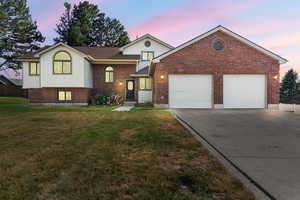 Split level home with an attached garage, driveway, brick siding, and a shingled roof