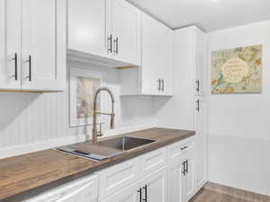 Kitchen with butcher block counters, white cabinetry, and dishwasher