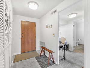 Foyer entrance with a textured ceiling and carpet floors