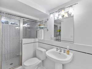 Bathroom with a shower stall, tile walls, and a wainscoted wall