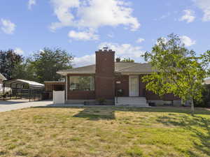 View of front facade featuring a carport, a chimney, driveway, and a shingled roof
