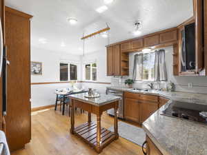 Kitchen with brown cabinets, tile countertops, appliances with stainless steel finishes, ceiling fan, and open shelves
