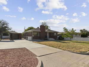 Single story home featuring a detached carport, a chimney, and concrete driveway