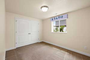 Unfurnished bedroom with carpet, a closet, and a textured ceiling