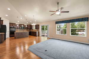 Kitchen with lofted ceiling, a center island, dark brown cabinets, decorative backsplash, and a chandelier