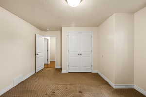 Unfurnished bedroom featuring carpet floors, a textured ceiling, and a closet