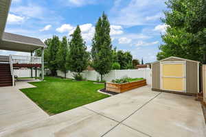 Fenced backyard with a patio area, a shed, a garden, stairs, and a deck