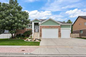 View of front facade with board and batten siding, a garage, concrete driveway, and brick siding