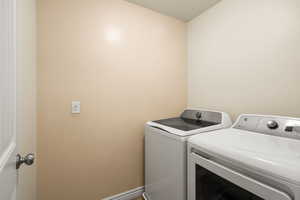 Laundry area with washing machine and dryer and baseboards