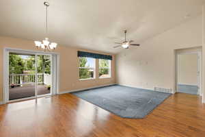 Unfurnished room featuring vaulted ceiling, a chandelier, wood finished floors, and a ceiling fan
