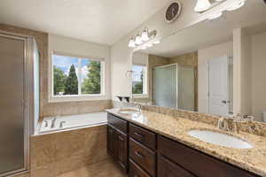 Full bath with a shower stall, double vanity, a bath, tile patterned flooring, and a textured ceiling
