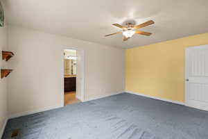 Unfurnished bedroom with carpet floors, ensuite bathroom, and a ceiling fan