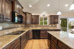 Kitchen featuring black appliances, dark brown cabinetry, light wood-type flooring, decorative light fixtures, and recessed lighting