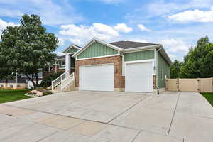 Ranch-style house featuring a gate, an attached garage, board and batten siding, concrete driveway, and brick siding