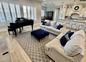 Living room featuring wood finished floors, ornamental molding, healthy amount of natural light, a chandelier, and recessed lighting