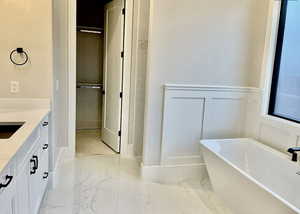 Full bath featuring a freestanding bath, vanity, and marble finish floors