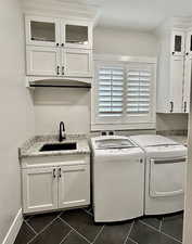 Washroom with washer and dryer, dark tile patterned floors, cabinet space, and bar with sink