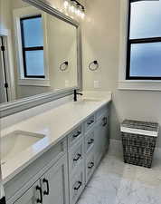 Full bath with marble finish floors and double vanity