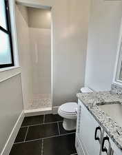 Bathroom with vanity, tile patterned flooring, and tiled shower