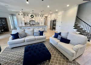 Living area featuring light wood-type flooring, ornamental molding, stairs, and recessed lighting