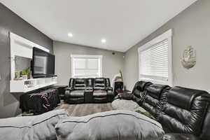 Cinema with light wood-style floors, vaulted ceiling, and recessed lighting