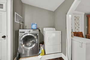 Washroom with washing machine and dryer and dark wood-type flooring