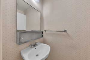 Bathroom with a sink and wallpapered walls