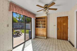 Spare room with wallpapered walls, light flooring, a baseboard heating unit, and ceiling fan