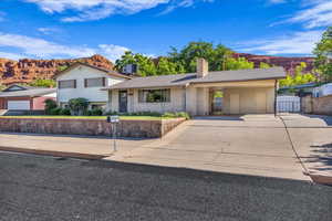 Split level home featuring a mountain view, concrete driveway, a chimney, and brick siding
