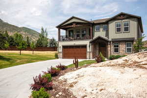 Craftsman inspired home with a balcony, concrete driveway, stone siding, an attached garage, and a mountain view